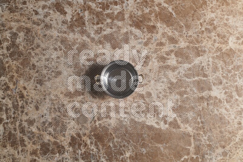 A small copper pot on beige marble background