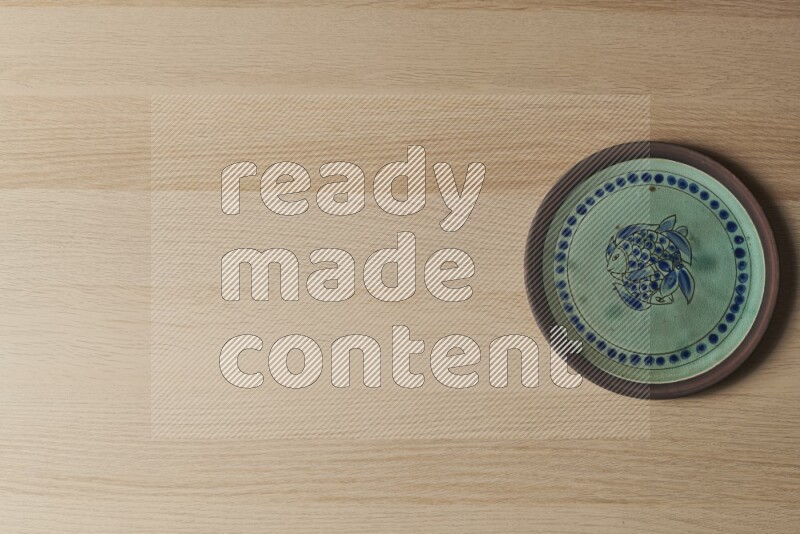A decorative pottery plate on light wooden background