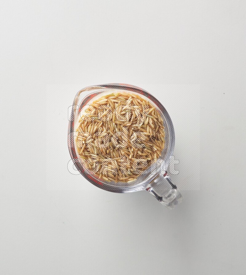 Top-view shot of long grain brown rice in a container on white background