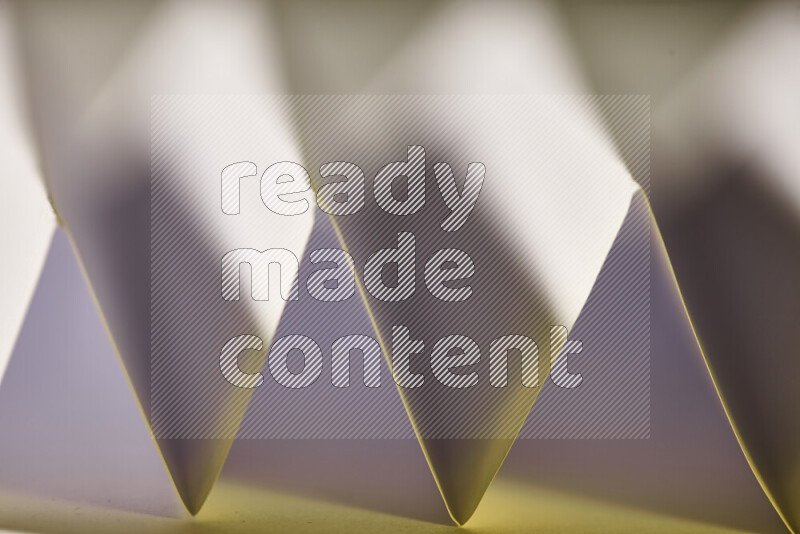 A close-up abstract image showing sharp geometric paper folds in white gradients and warm tones