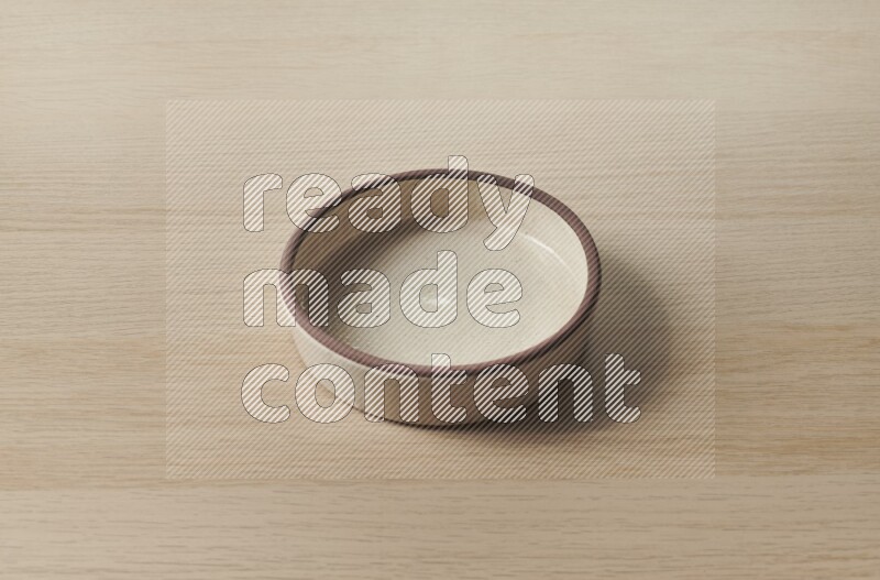 A beige pottery oven bowl on light wooden background