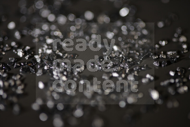 Black shimmering fragments of glass scattered on a black background