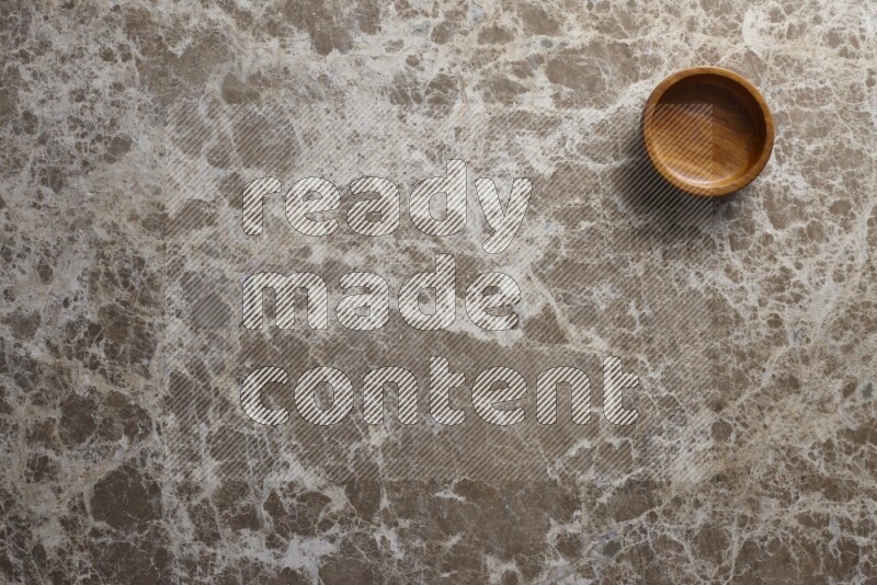 A wooden bowl on beige marble background