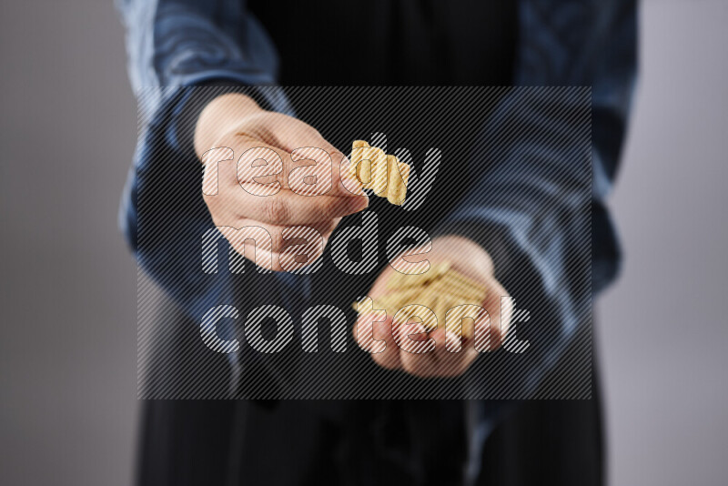 Woman in abaya holding different kinds of snacks in different positions