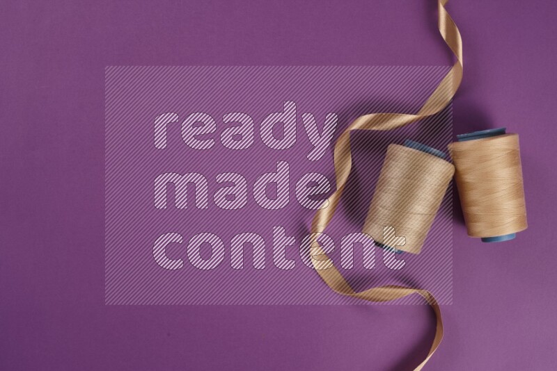 A beige collection of sewing and tailoring tools arranged on a purple background