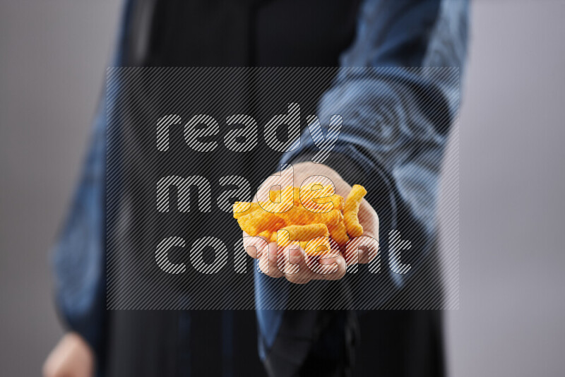 Woman in abaya holding different kinds of snacks in different positions