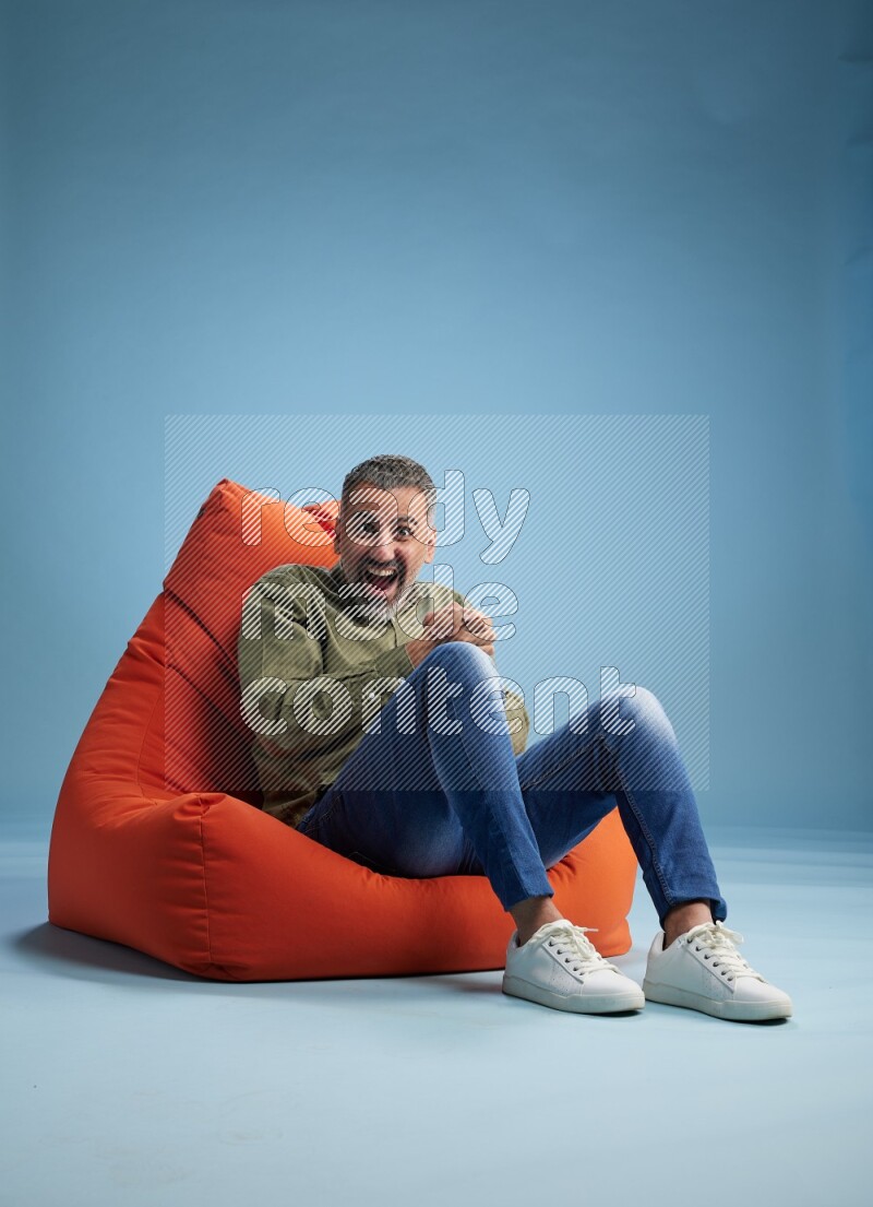 A man sitting on an orange beanbag and interacting with the camera