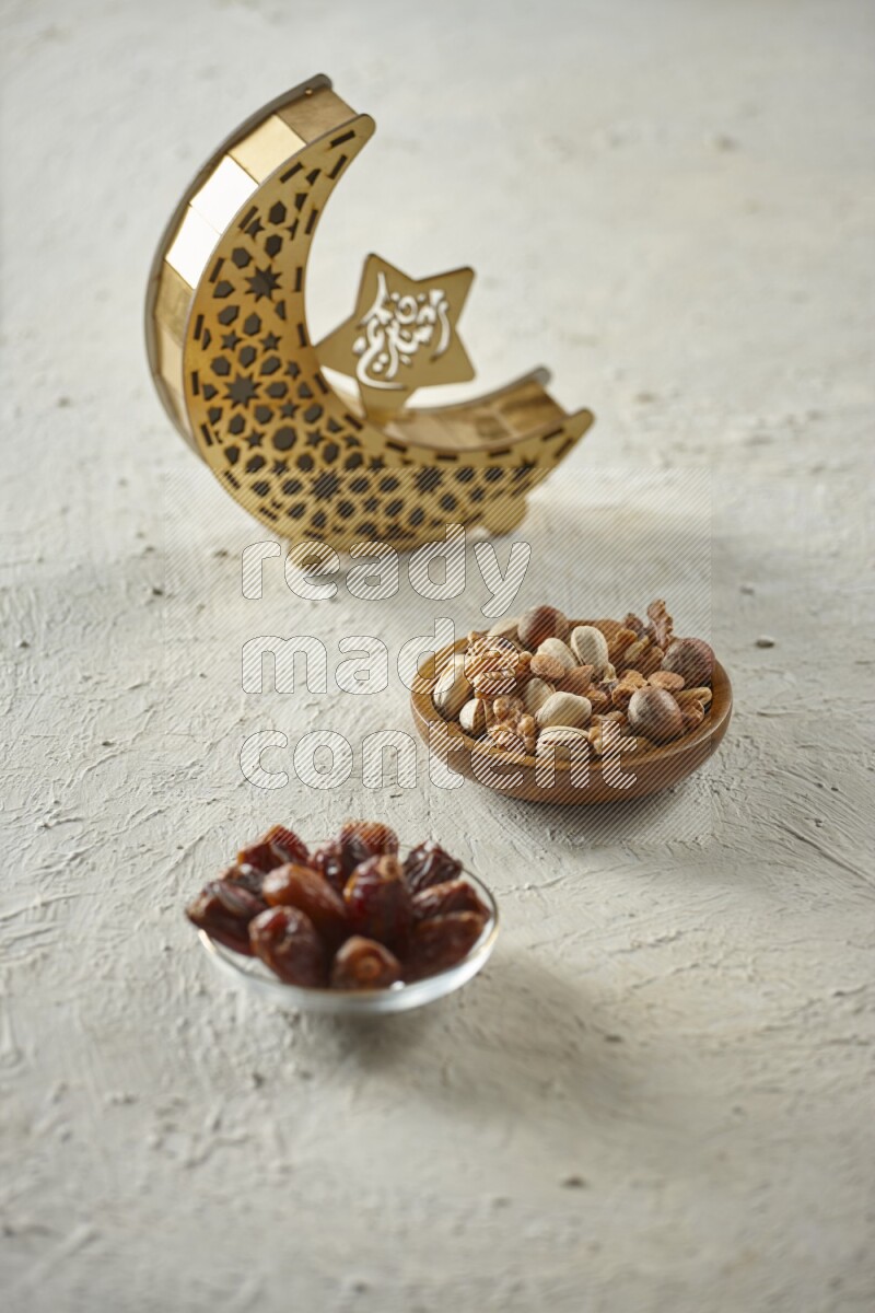 A wooden golden crescent lantern with different drinks, dates, nuts, prayer beads and quran on white background