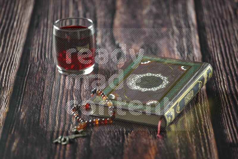 Quran with dates, prayer beads and different drinks all placed on wooden background