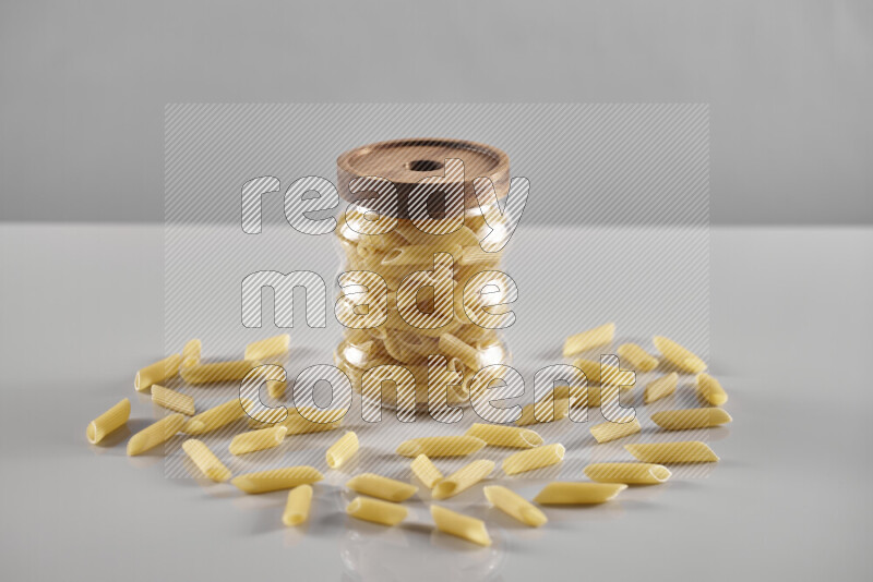 Raw pasta in a glass jar on light grey background