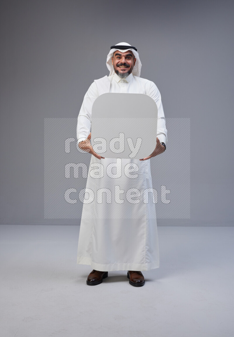 Saudi man Wearing Thob and white Shomag standing holding social media sign on Gray background
