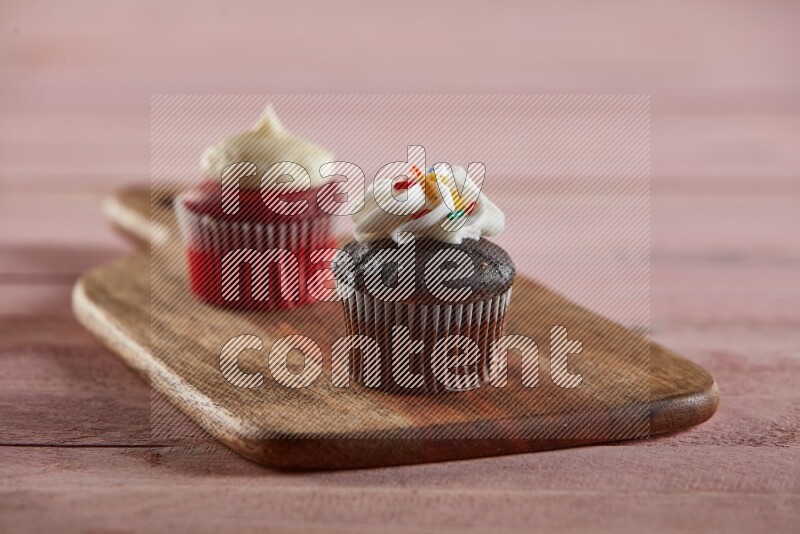Chocolate mini cupcake topped with cream on a wooden board