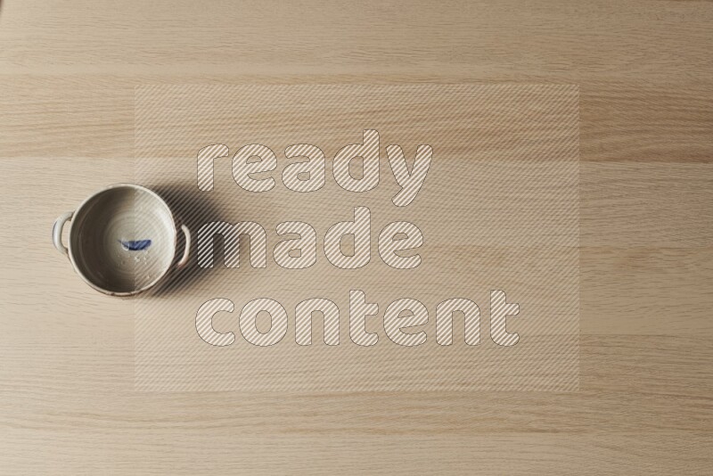 A multicolored pottery bowl on light wooden background