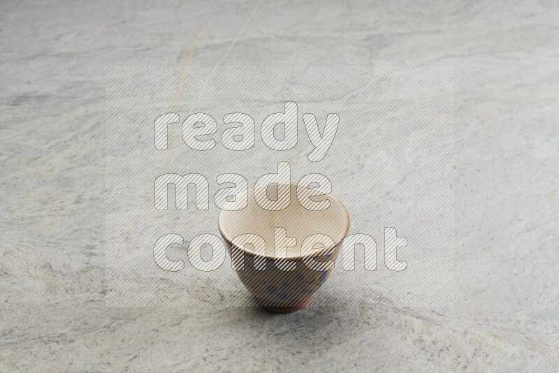 A multicolored pottery bowl on grey marble background