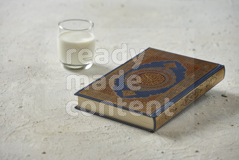 Quran with dates, prayer beads and different drinks all placed on textured white background
