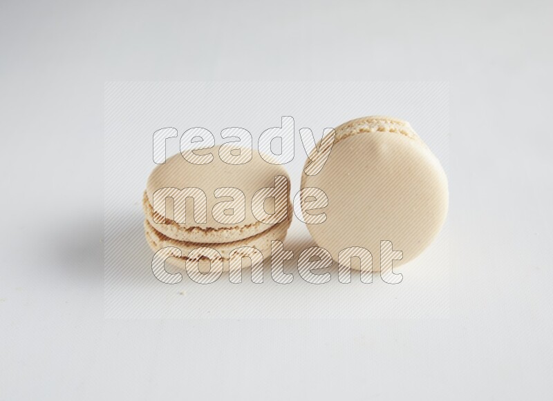 45º Shot of two White Caramel fleur de sel macarons on white background