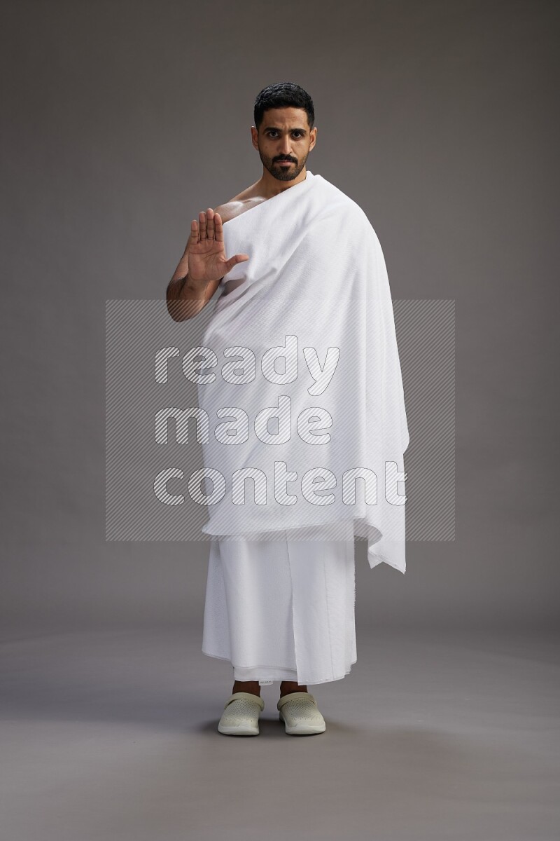 A man wearing Ehram Standing Interacting with the camera on gray background