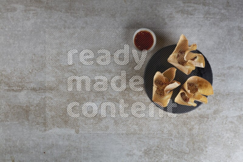 wonton cups with soy sauce ramkin on circle slate on grey textured counter top