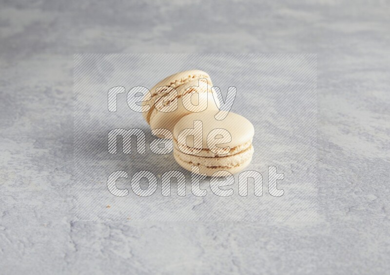 45º Shot of two white marbleCaramel fleur de sel macarons  on white  marble background