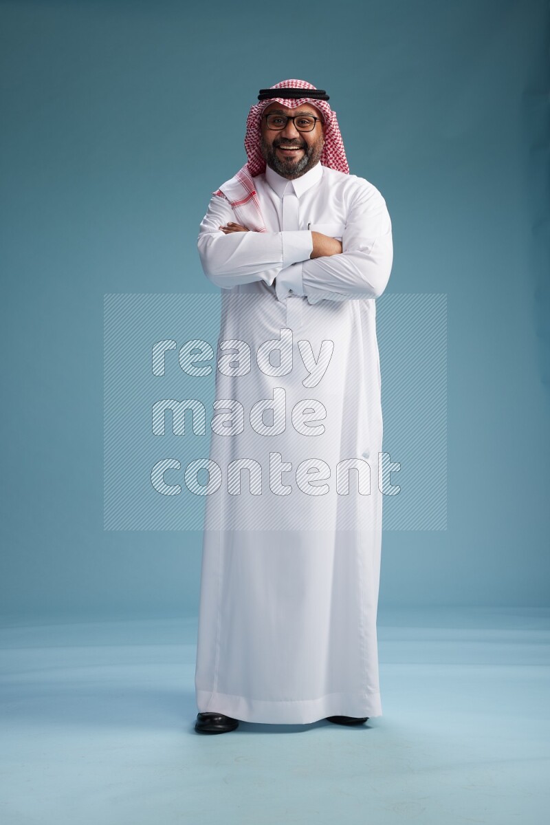 Saudi Man with shimag Standing Interacting with the camera on blue background