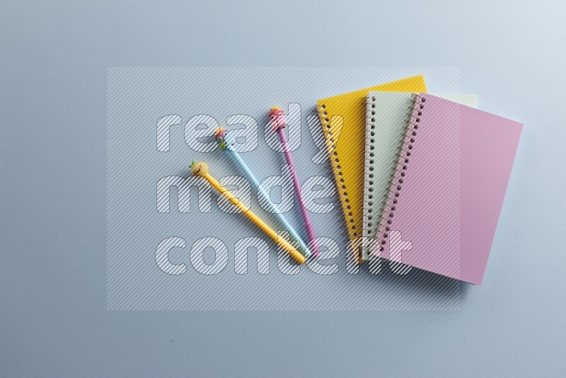Multicolored notebooks with different school supplies on blue background