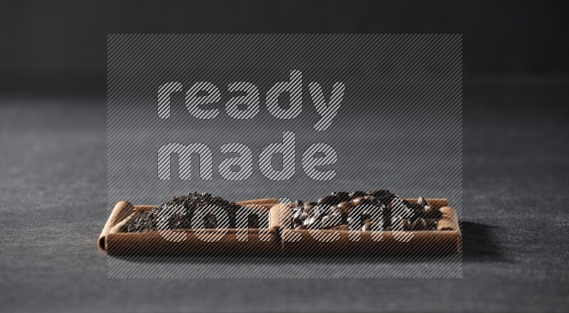 مربعان من أعواد القرفة ممتلئان بحبوب القهوة والشاي الأسود علي خلفية سوداء