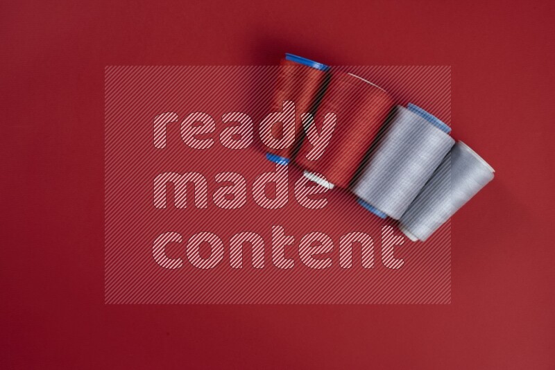 A grey collection of sewing and tailoring tools arranged on a red background