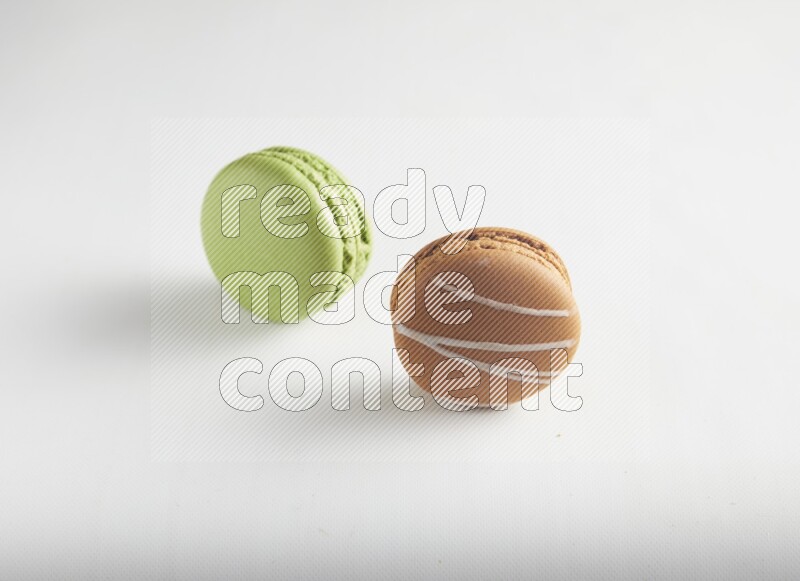 45º Shot of of two assorted Brown Irish Cream, and Green Pistachio macarons on white background