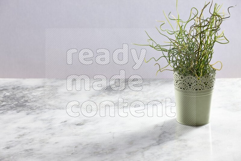 Artificial plant in green decorative pot on grey marble background