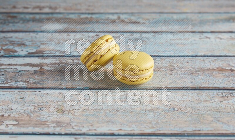 45º Shot of two Yellow Lime macarons on light blue wooden background
