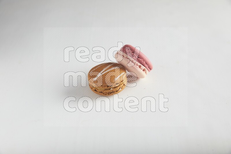 45º Shot of of two assorted Brown Irish Cream, and Pink Litchi Raspberry macarons on white background