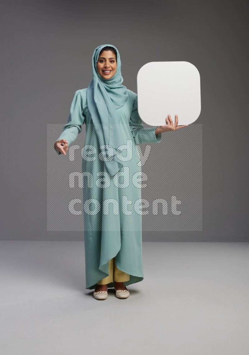 Saudi Woman wearing Abaya standing holding social media sign on Gray background