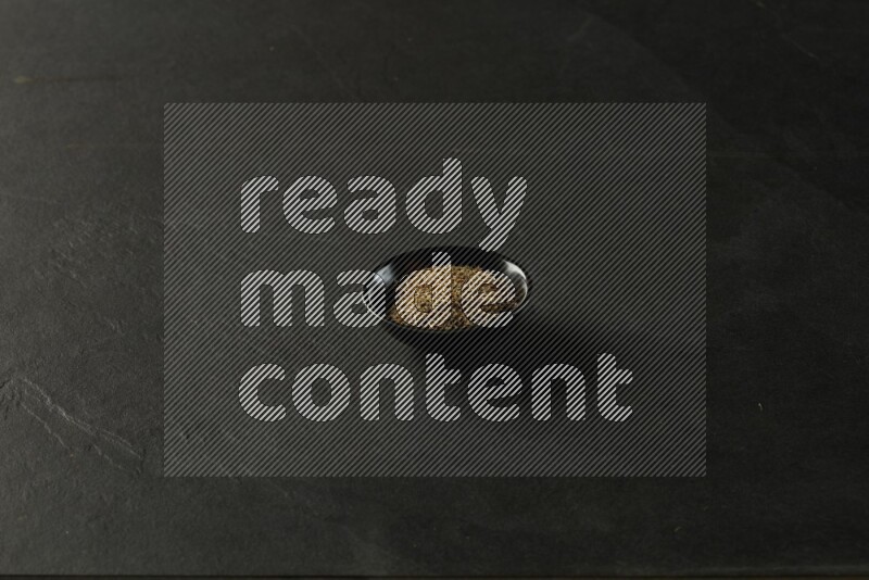 black pottery round sauce bowl filled with herbs on grey textured countertop