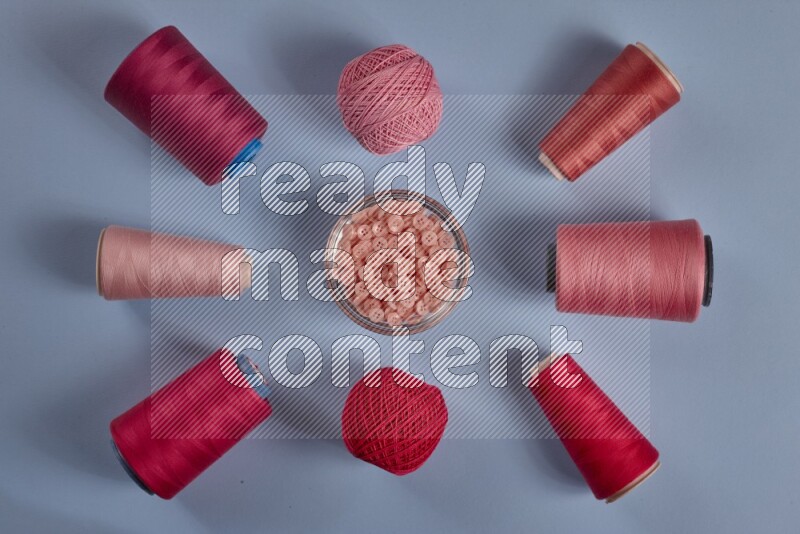A pink collection of sewing and tailoring tools arranged on a blue background