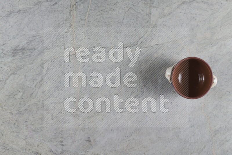 A multicolored pottery pot with its lid on grey marble background