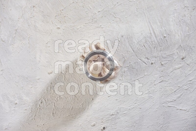 وعاء توابل زجاجي ممتلئ بفصوص الثوم علي خلفية بيضاء