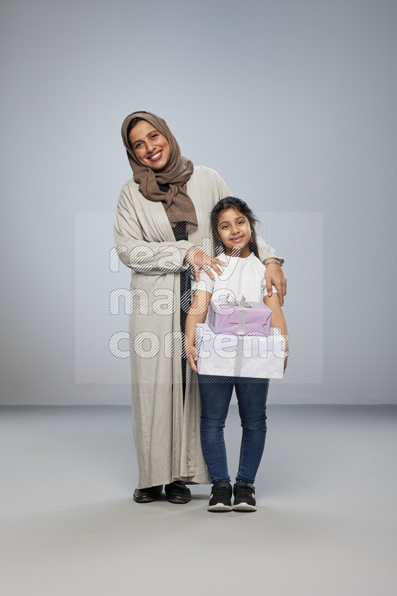 A girl giving a gift to her mother on gray background