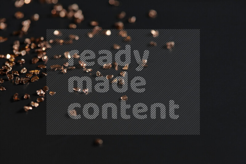 Bronze shimmering fragments of glass scattered on a black background