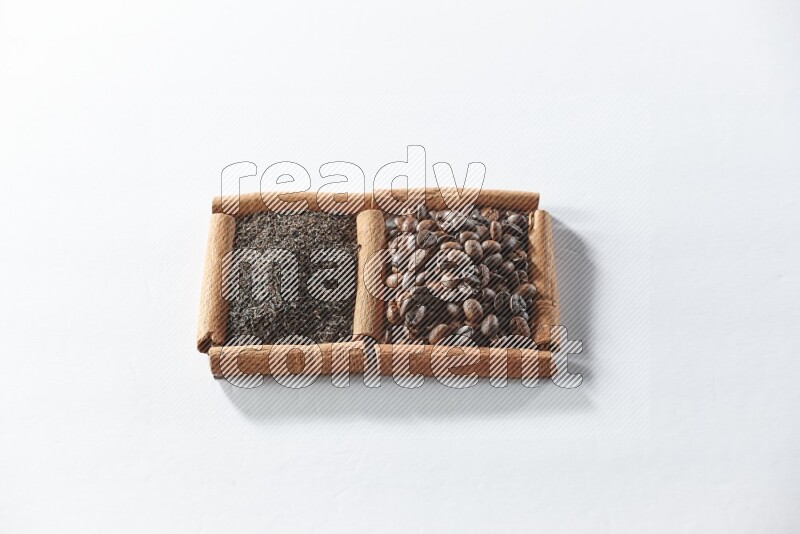 مربعان من أعواد القرفة ممتلئان بحبوب القهوة والشاي الأسود علي خلفية بيضاء