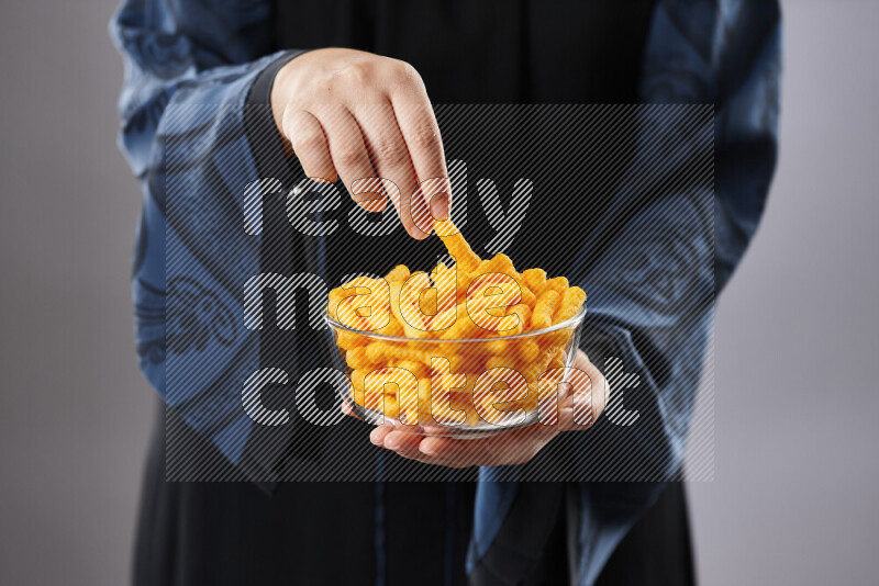 Woman in abaya holding different kinds of snacks in different positions