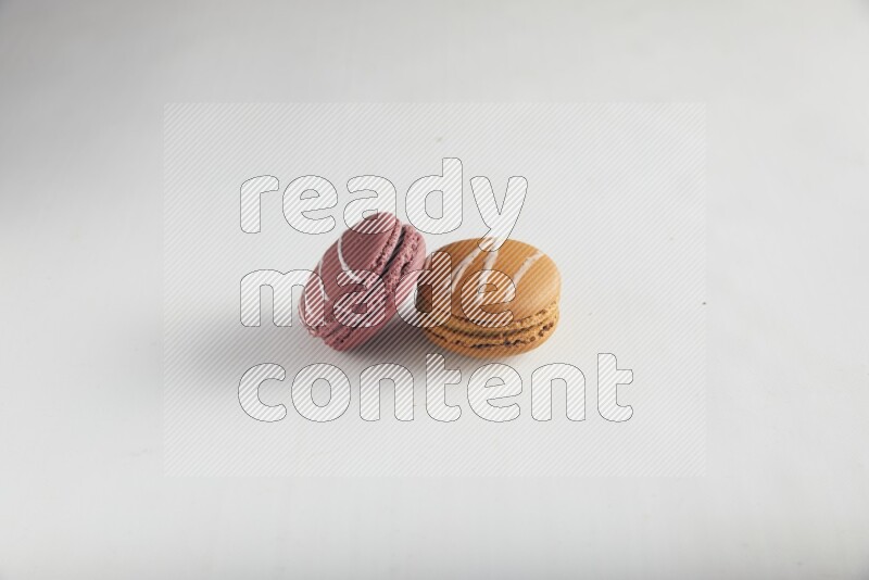45º Shot of of two assorted Brown Irish Cream, and Red Poppy Flower macarons on white background