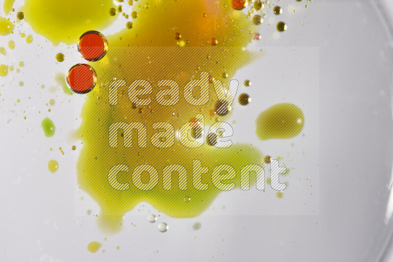 Close-ups of abstract red, green and yellow watercolor drops on oil Surface on white background