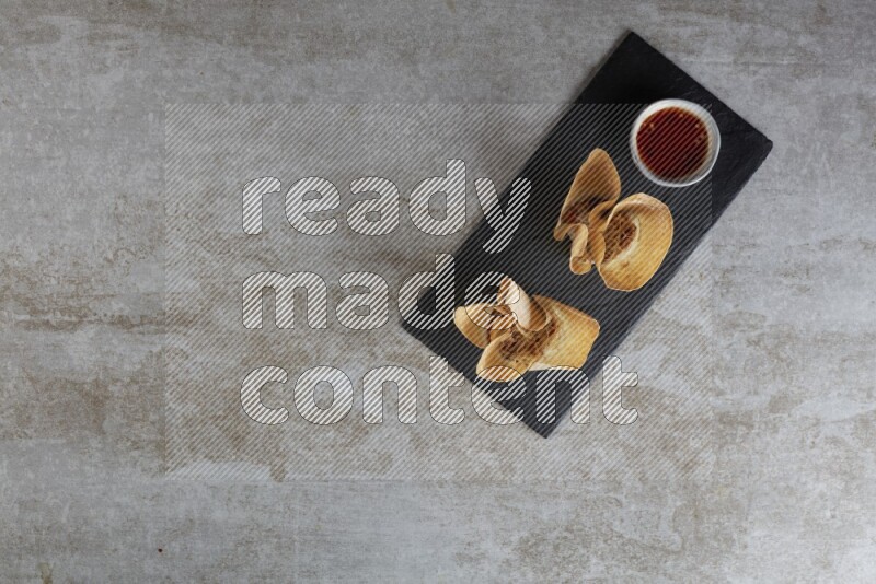 wonton cups with soy sauce ramkin on rectangle slate on grey textured counter top