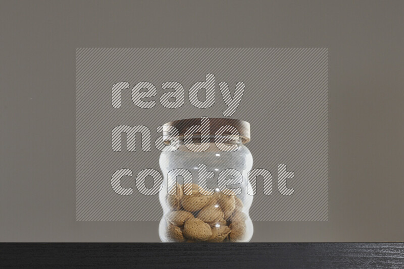 Almonds in a glass jar on black background