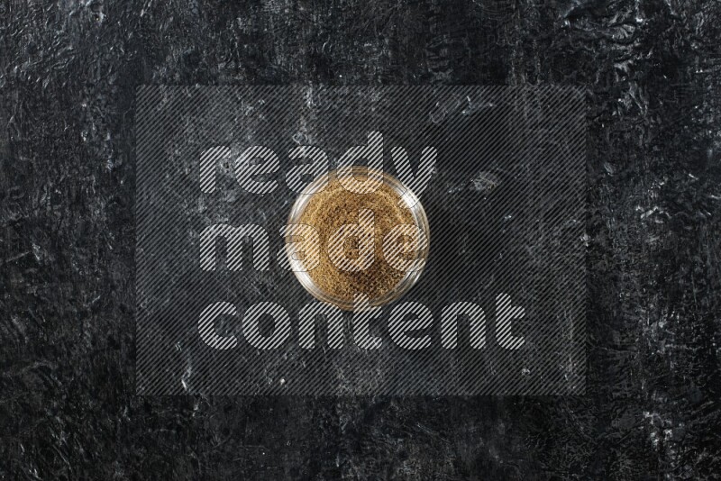 وعاء زجاجي ممتلئ ببودرة الكمون على خلفية سوداء