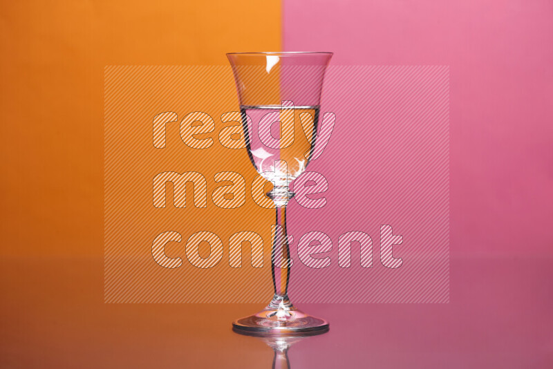 The image features a clear glassware filled with water, set against orange and pink background