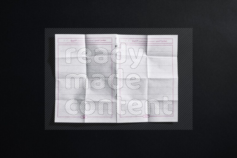Folded notebook sheet on black background