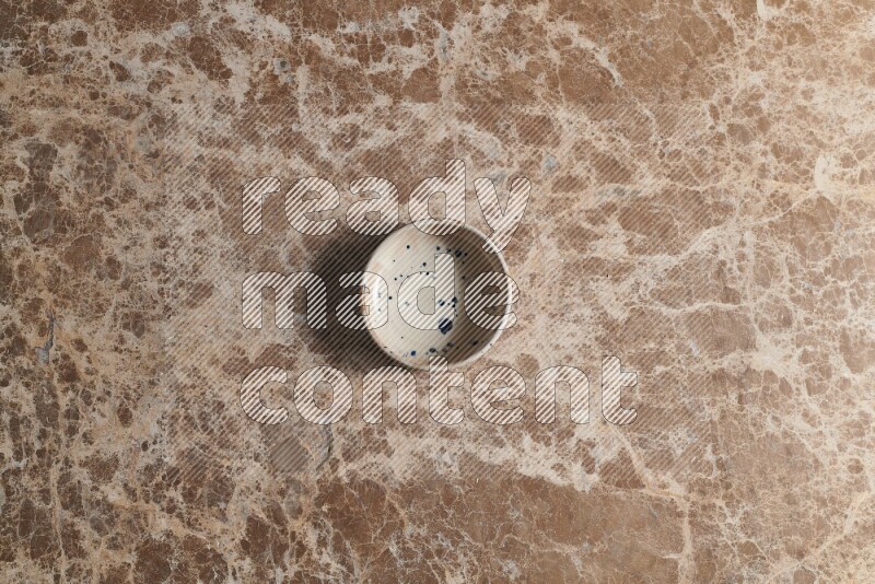 A multicolored pottery bowl on beige marble background