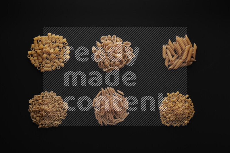 Different pasta types in bunches on black background