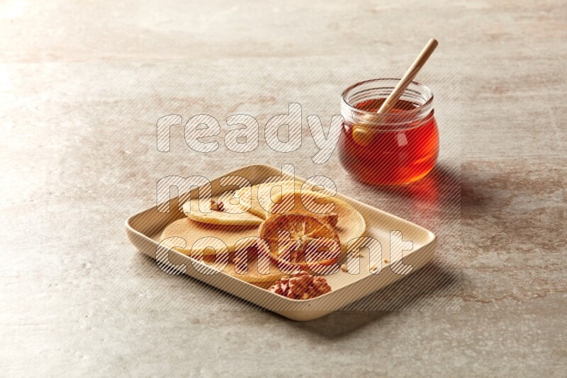 Five stacked dried orange mini pancakes in a rectangular plate on beige background